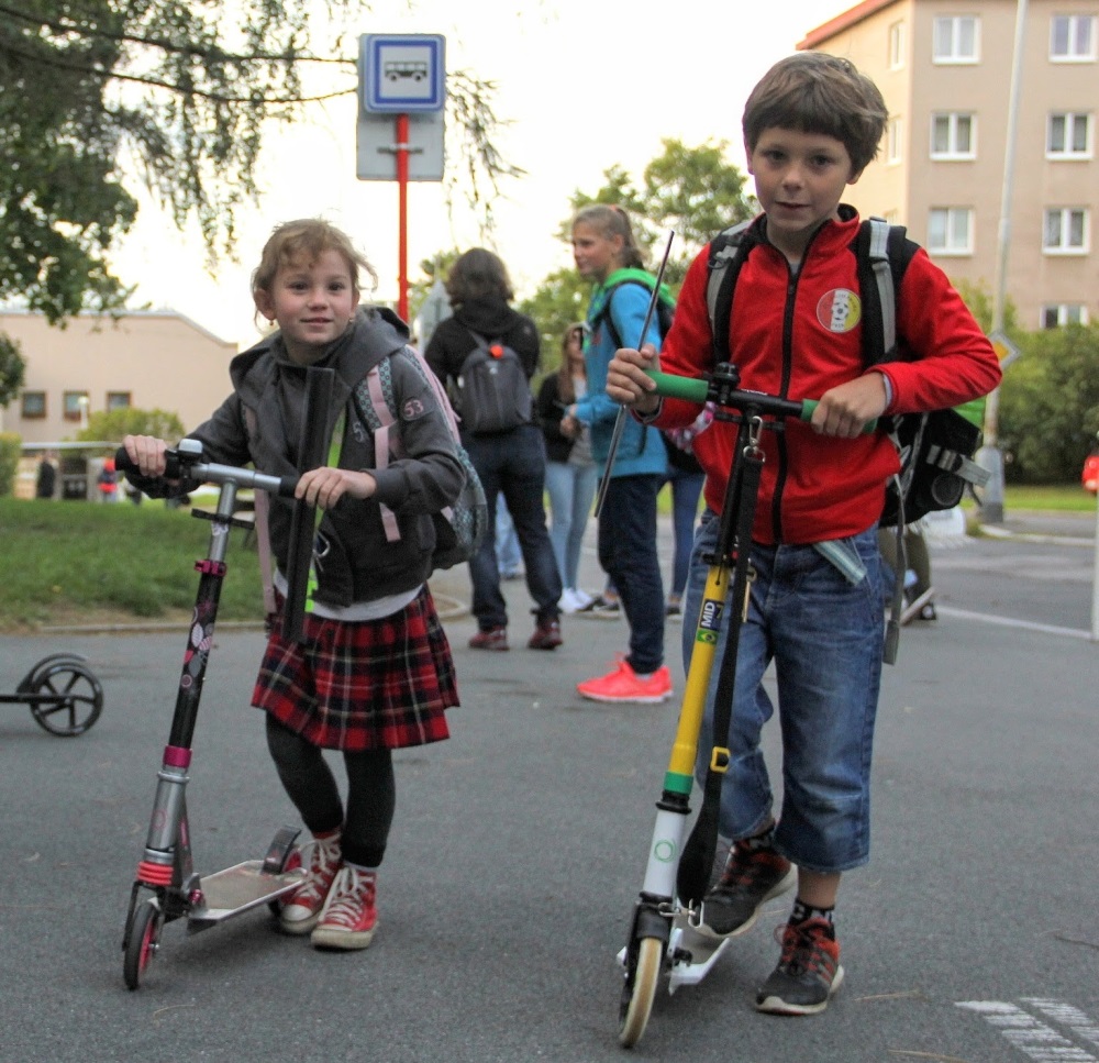 děti s koloběžkami před školou