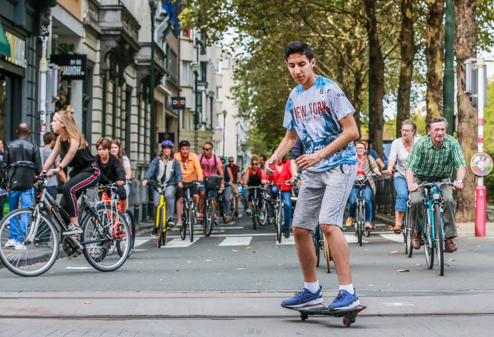 mnoho cyklistů, před nimi jezdec na skateboardu