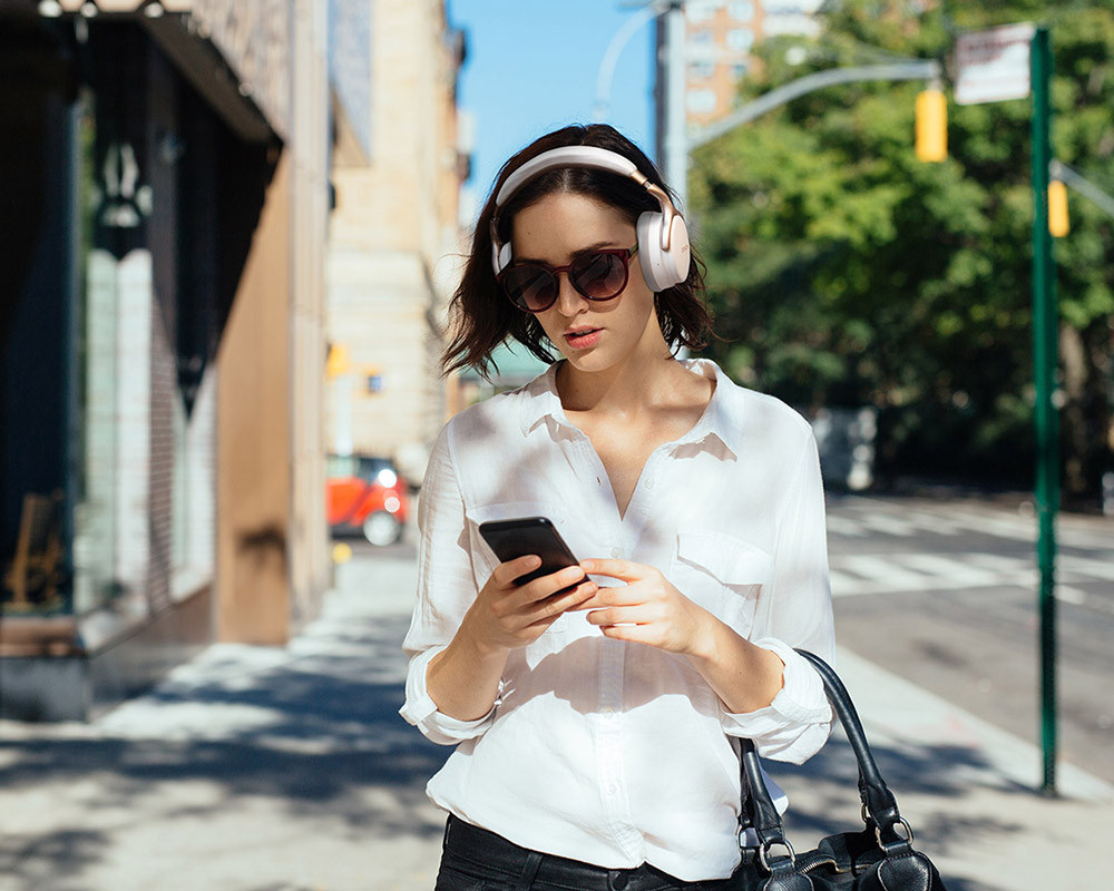 foto ženy se sluchátky na uších, navíc sledující mobil