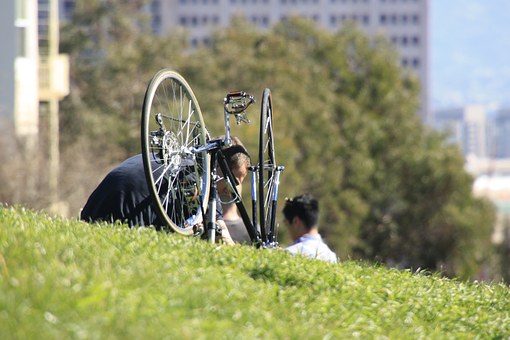 krásný den, kolo odložené v trávě, za ním na trávě sedí lidé