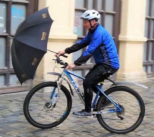 jedoucí cyklista s otevřeným deštníkem
