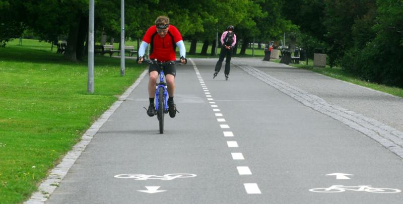 foto - vepředu jezdec na kole, za ním inline bruslař