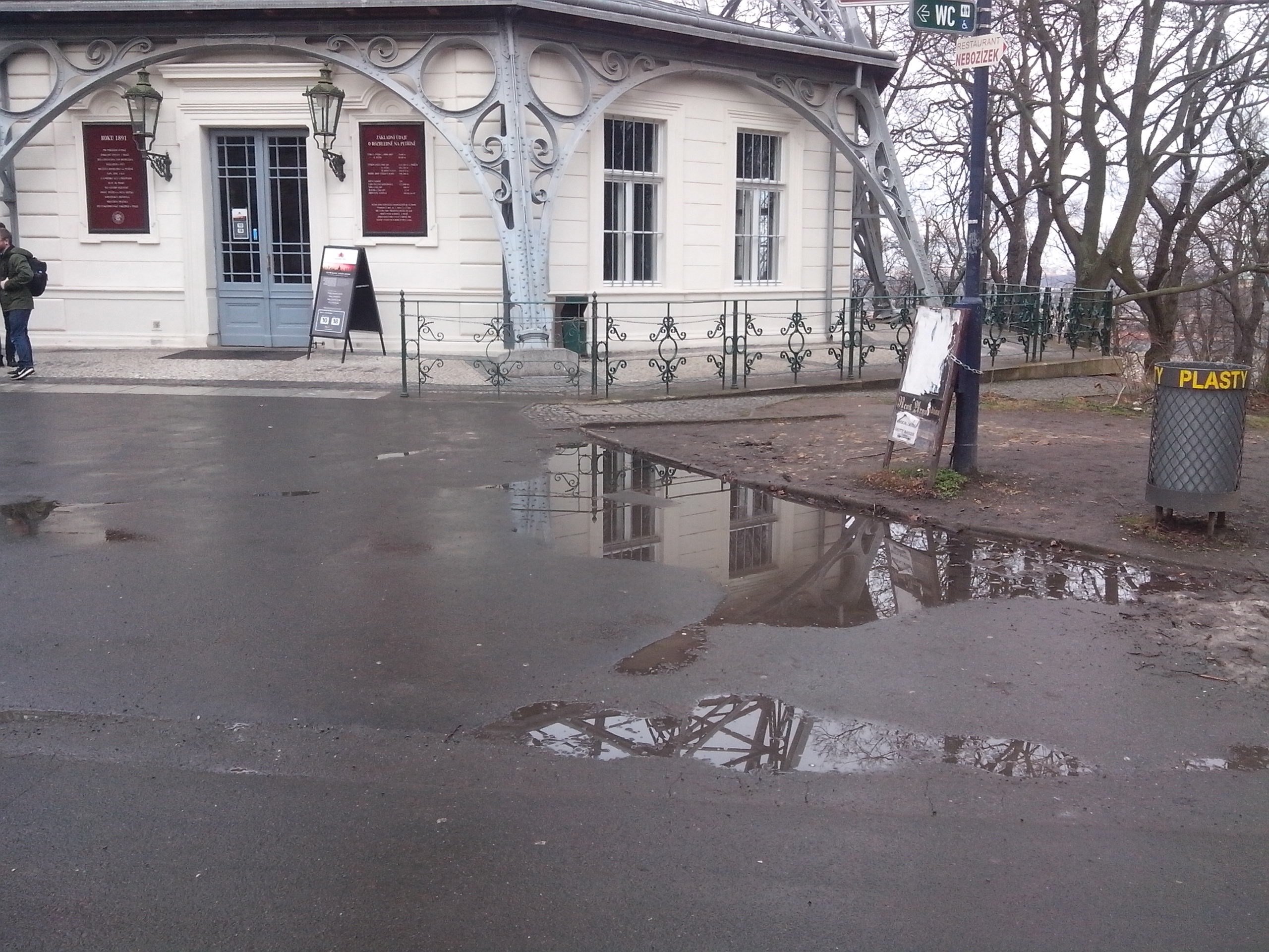 Nevzhledný asfalt s loužemi před rozhlednou