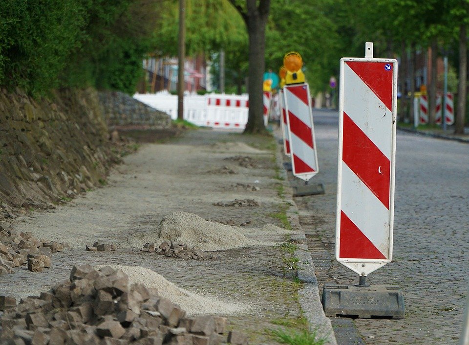 opravující se chodník a silnice s dopravními značkami 