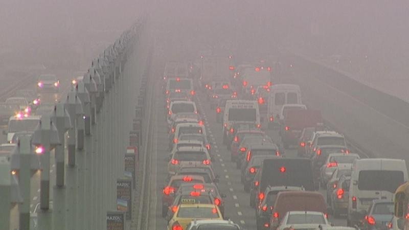 řady automobilů na slinici v hustém smogu