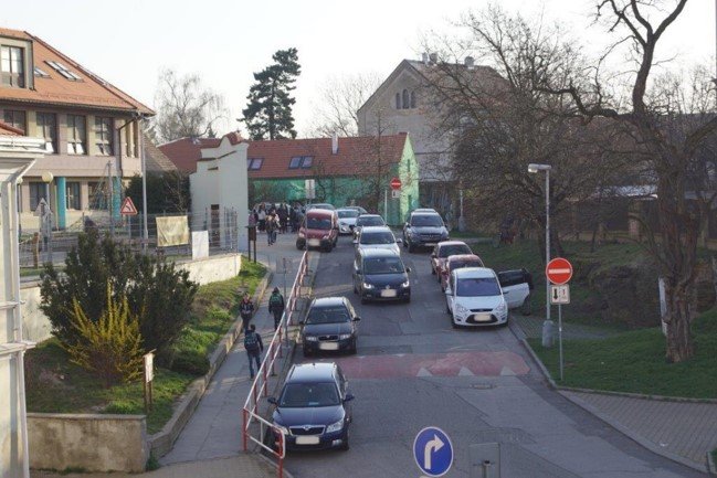 foto - mnoho aut před školou, nepřehledná situace