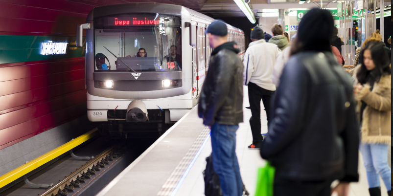 foto ze stanice metra - lidé na nástupišti se dívají na přijíždějící vůz
