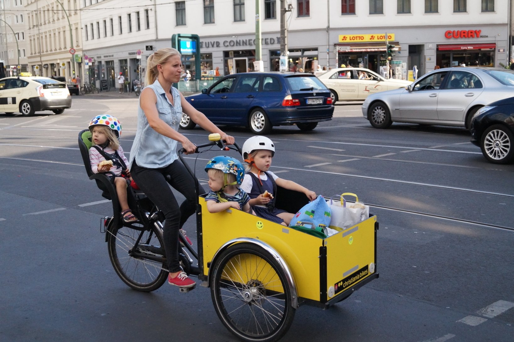 matka veze na kole tři děti - jedno vzadu, dvě vepředu