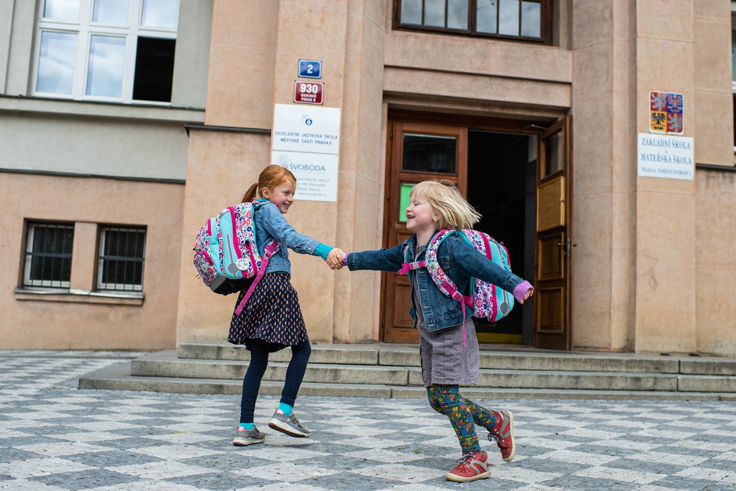 dvě hhrající si děti před vchodem do školy