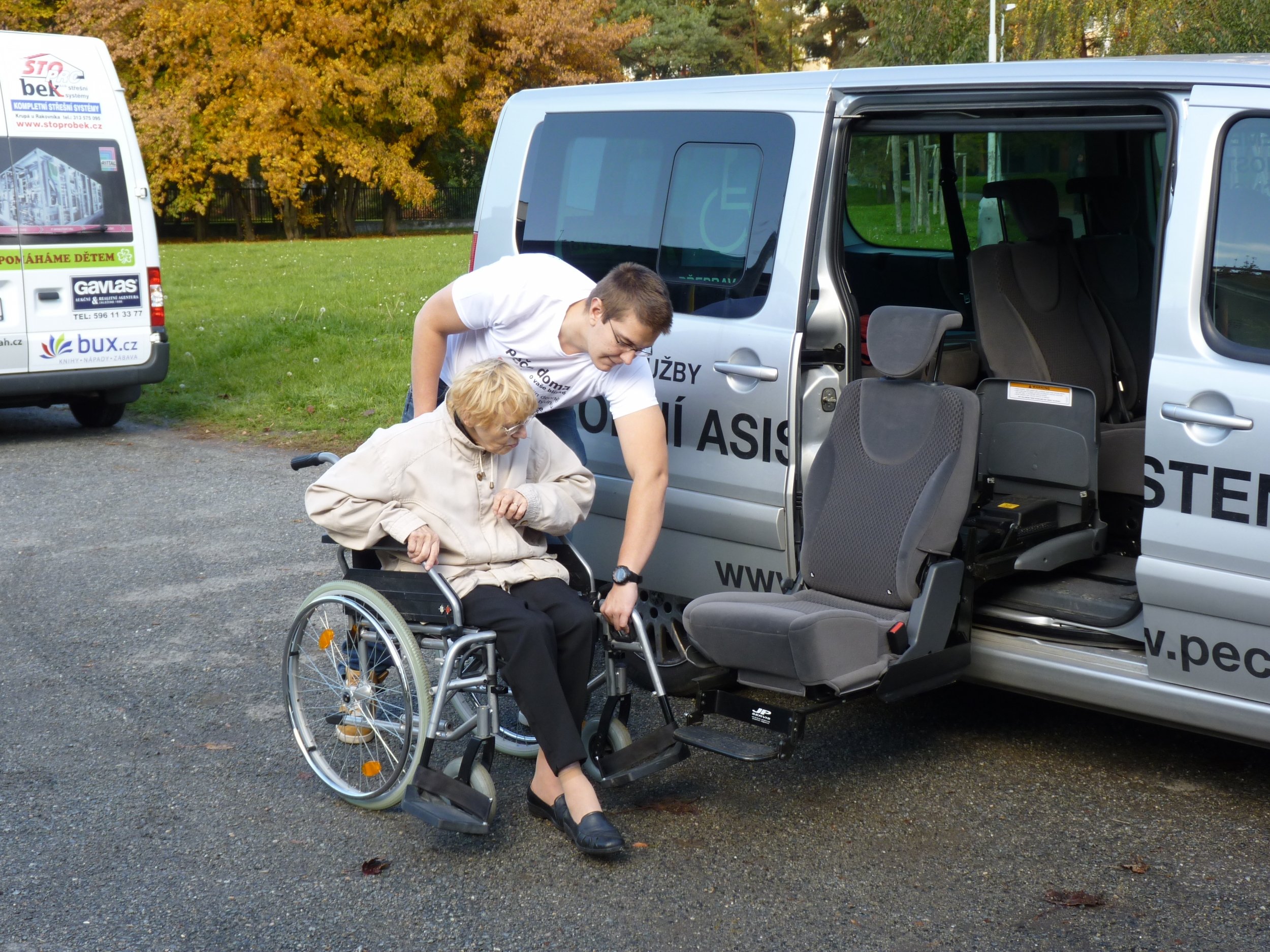 foto: muž pomáhá ženě na vozíčku do přepravního automobilu