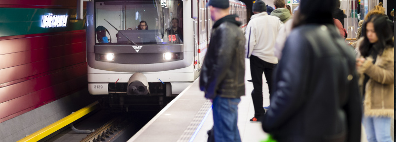 foto ze stanice metra - lidé na nástupišti se dívají na přijíždějící vůz