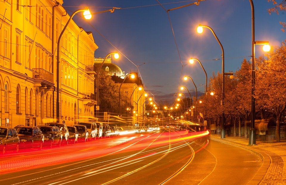 Noční ulice, rozmazaná auta i chodci