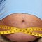 FOTO - DETAIL na břicho obézního muže, přes něj krejčovský metr
